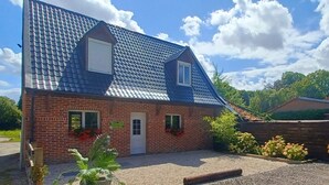 A two-story house with a sloped roof, brick exterior, and a small front porch. - Whole House (Wittes)