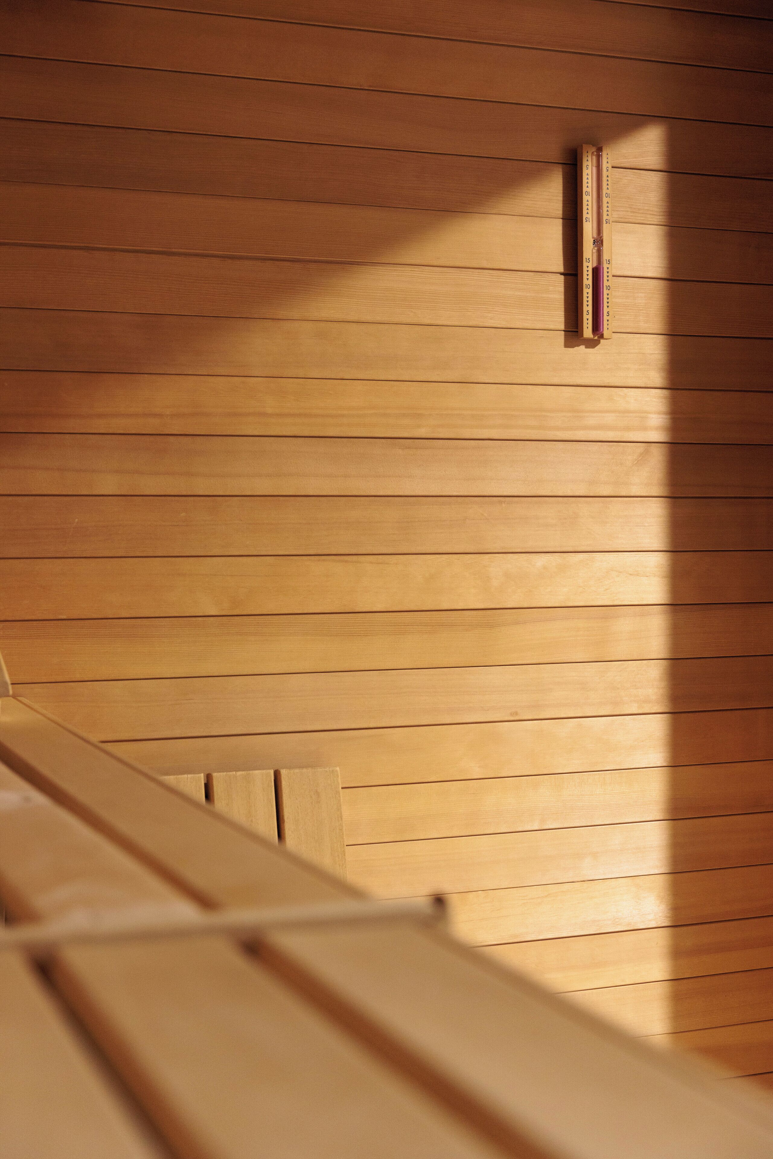 A wooden bench in a room with horizontal wooden paneling.