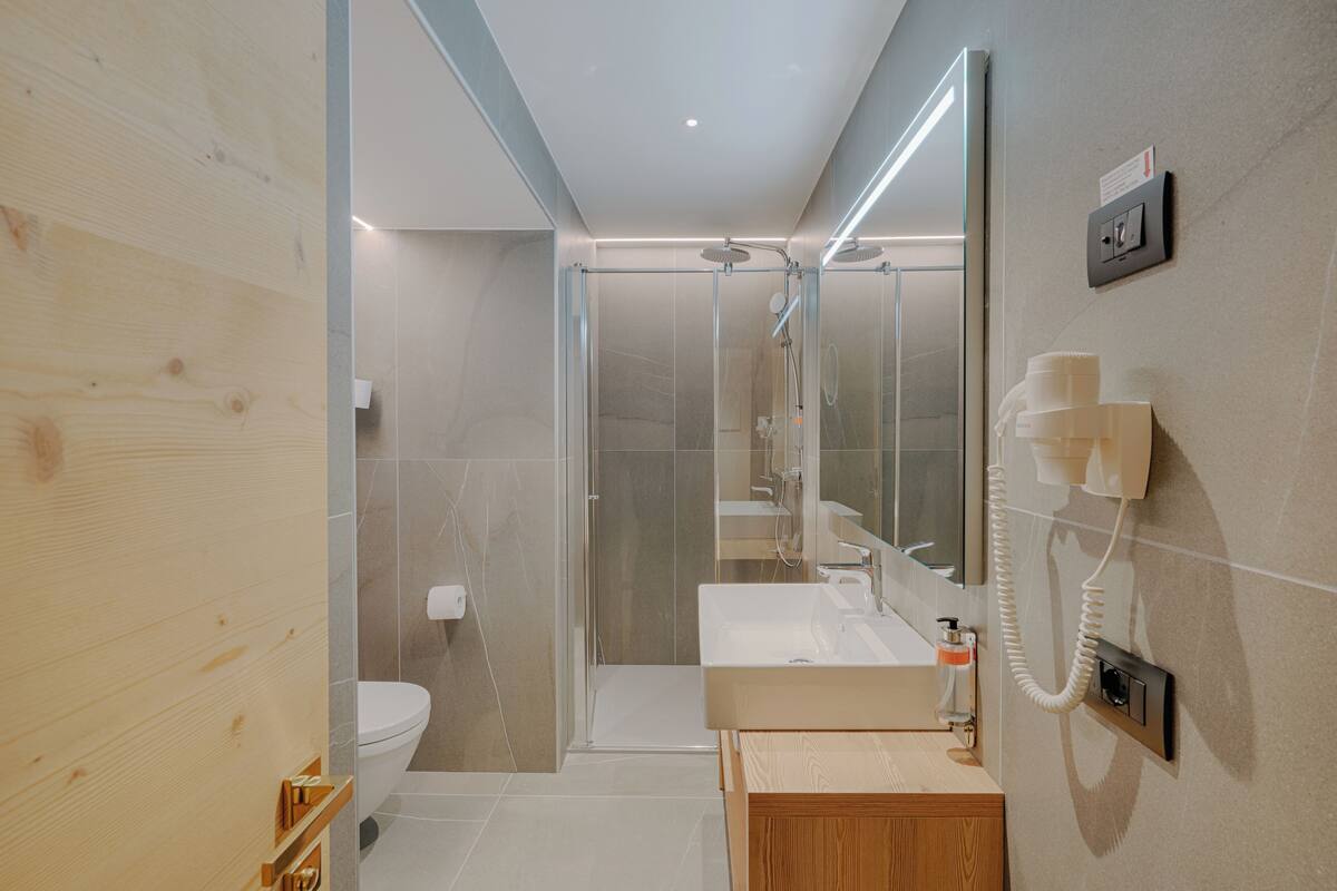 A modern bathroom with a glass-enclosed shower, a wooden vanity, and a large mirror.