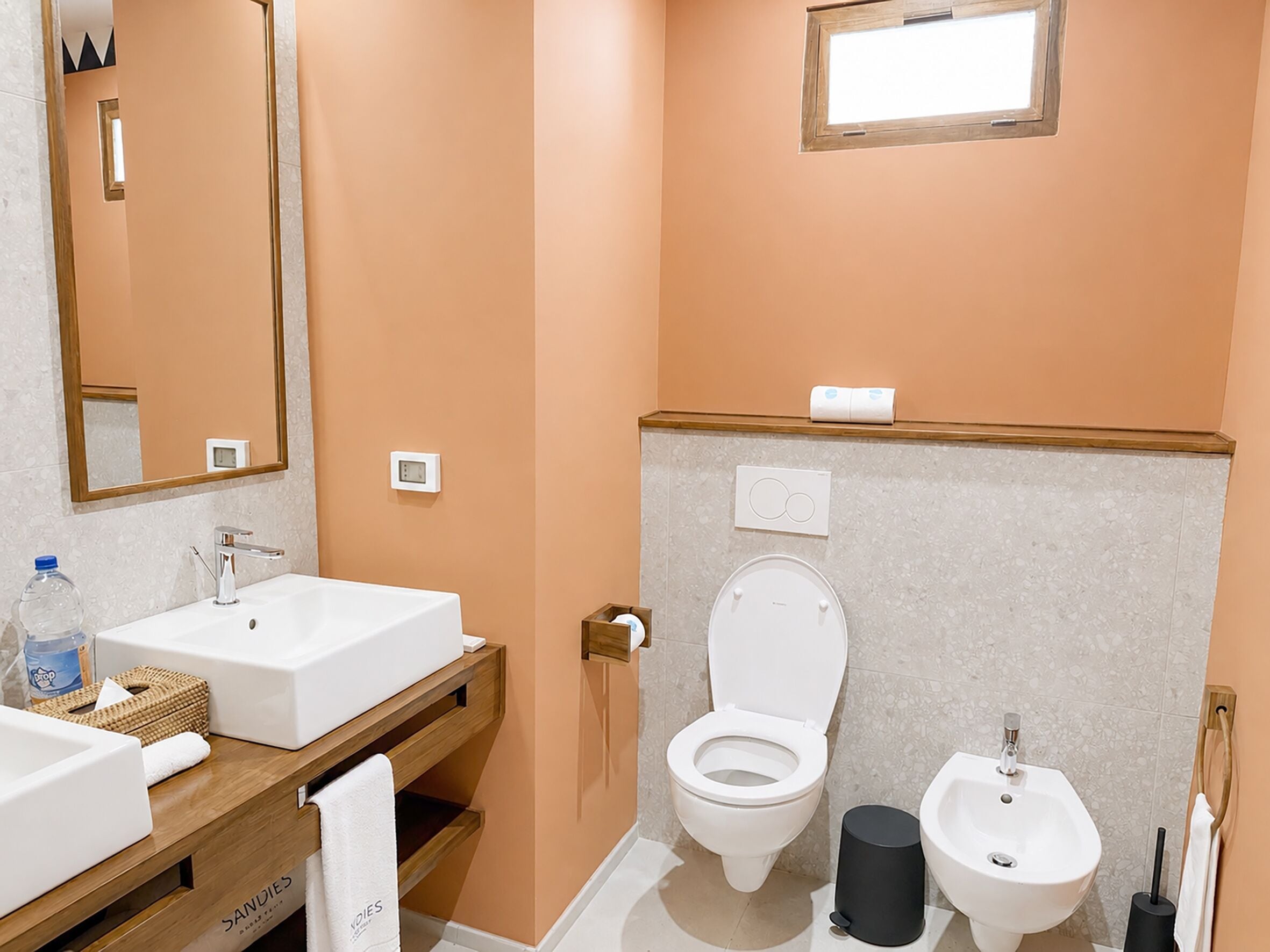 A bathroom with a sink, toilet, bidet, and mirror.