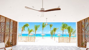 Habitación con vista al mar, ventilador de techo, suelo de piedra y divisiones de madera.