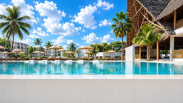 Una piscina de resort con sillas de descanso, palmeras y un edificio con techo de paja.
