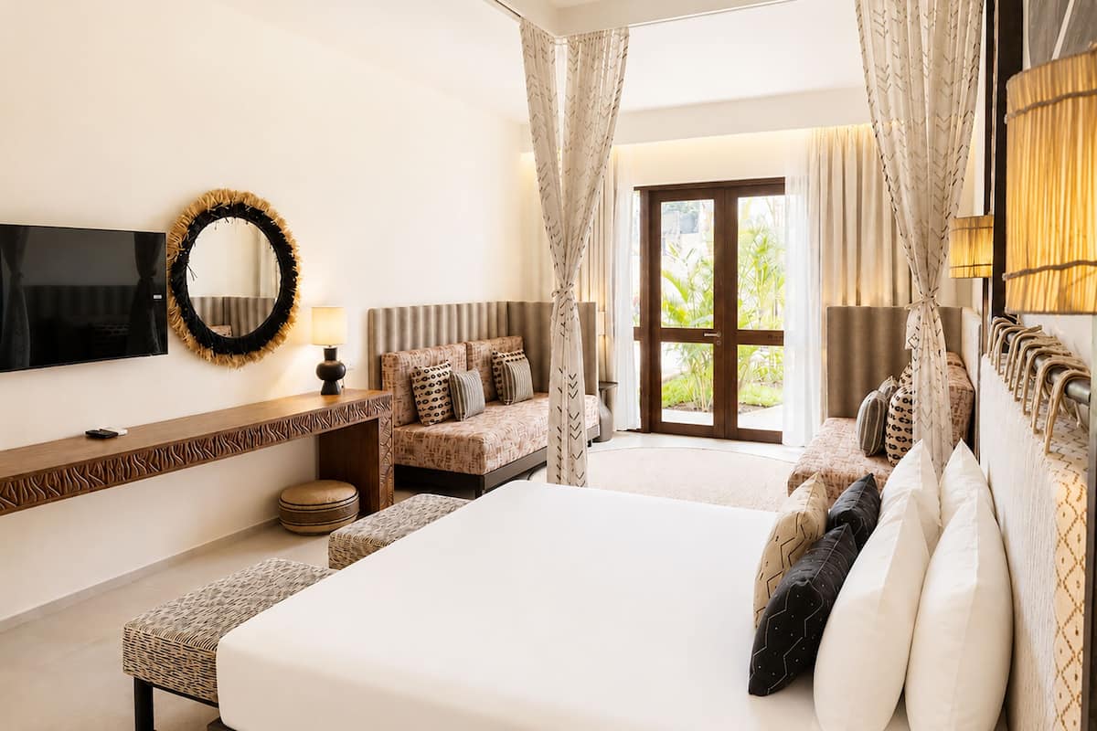 A hotel room with a bed, a TV, a desk, and a view of the outdoors.