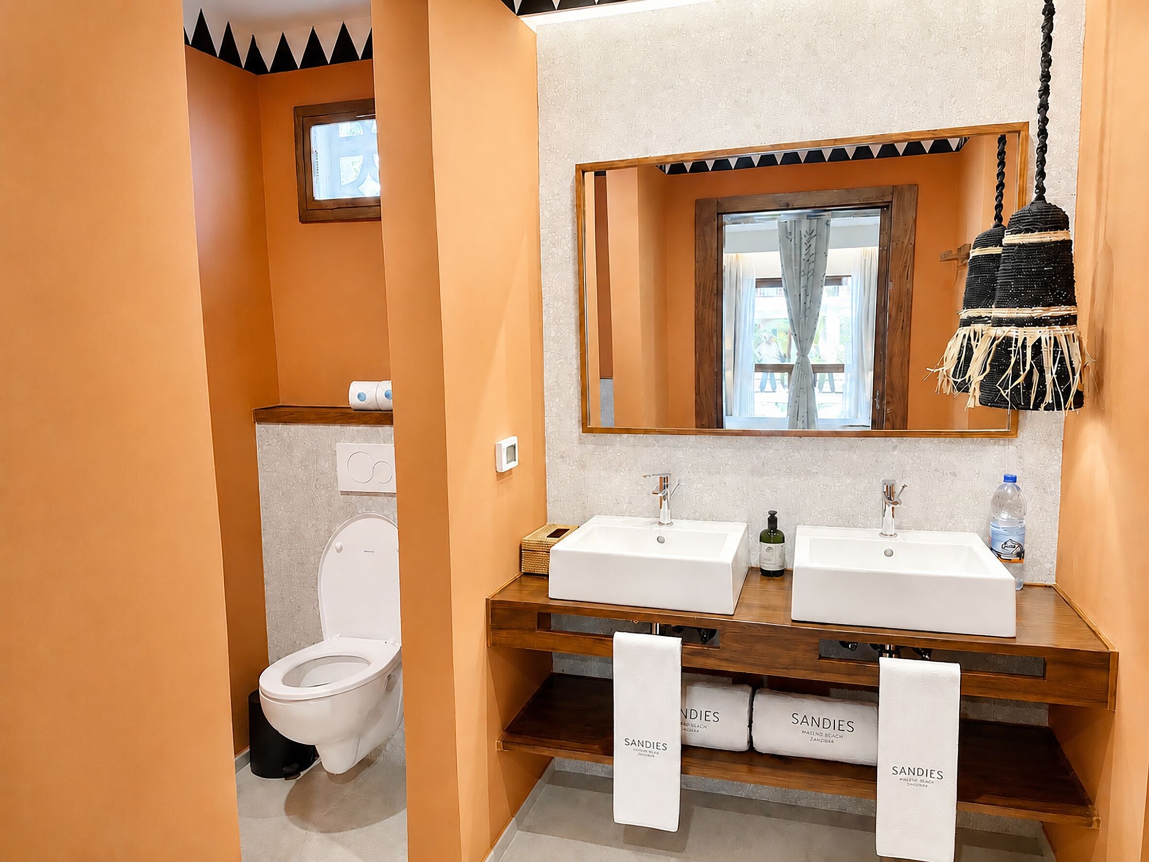 Un bagno con due lavandini, uno specchio e un appendi-asciugamani a parete.