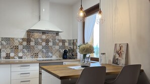 Eine moderne Küche mit einer großen Kochinsel, Pendelleuchten und einer gemusterten Spritzschutzwand.