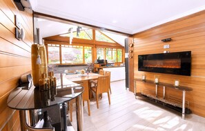 A modern kitchen with a flat-screen TV, wooden cabinetry, and a dining area with a round table and chairs.