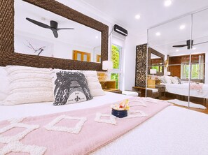 A modern bedroom with a large bed, a ceiling fan, and a view of the outdoors through a window. - Famous Palm Beach Home! 120-jet Spa Cabana, Games Room & Prime Central Location! (Sydney)