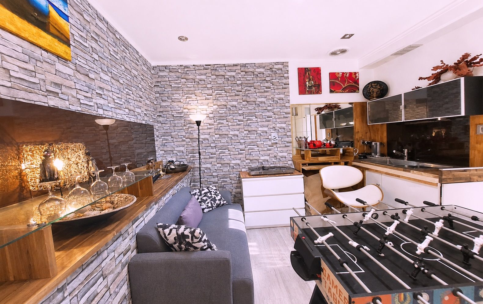 Una cocina moderna con salpicadero de piedra, mesa de fútbol y comedor con sofá y mesa.