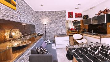 Una cocina moderna con salpicadero de piedra, mesa de fútbol y comedor con sofá y mesa.