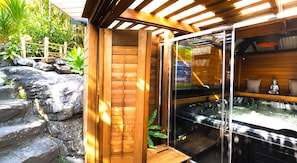 A wooden structure with a glass enclosure, a hot tub, and a rock garden. - Famous Palm Beach Home! 120-jet Spa Cabana, Games Room & Prime Central Location! (Sydney)