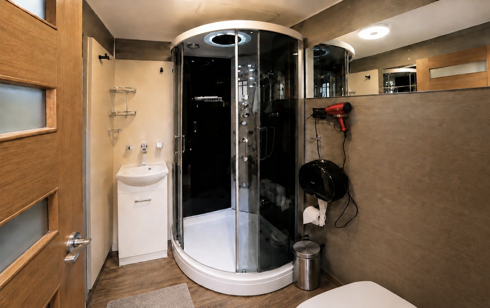 A modern bathroom with a glass-enclosed shower, a sink, and a hairdryer mounted on the wall.