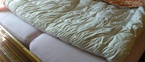 A bed with a patterned blanket and pillows, a striped rug, and a wooden headboard.