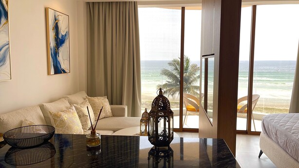 Ein modernes Hotelzimmer mit großem Fenster und Blick auf Strand und Meer.