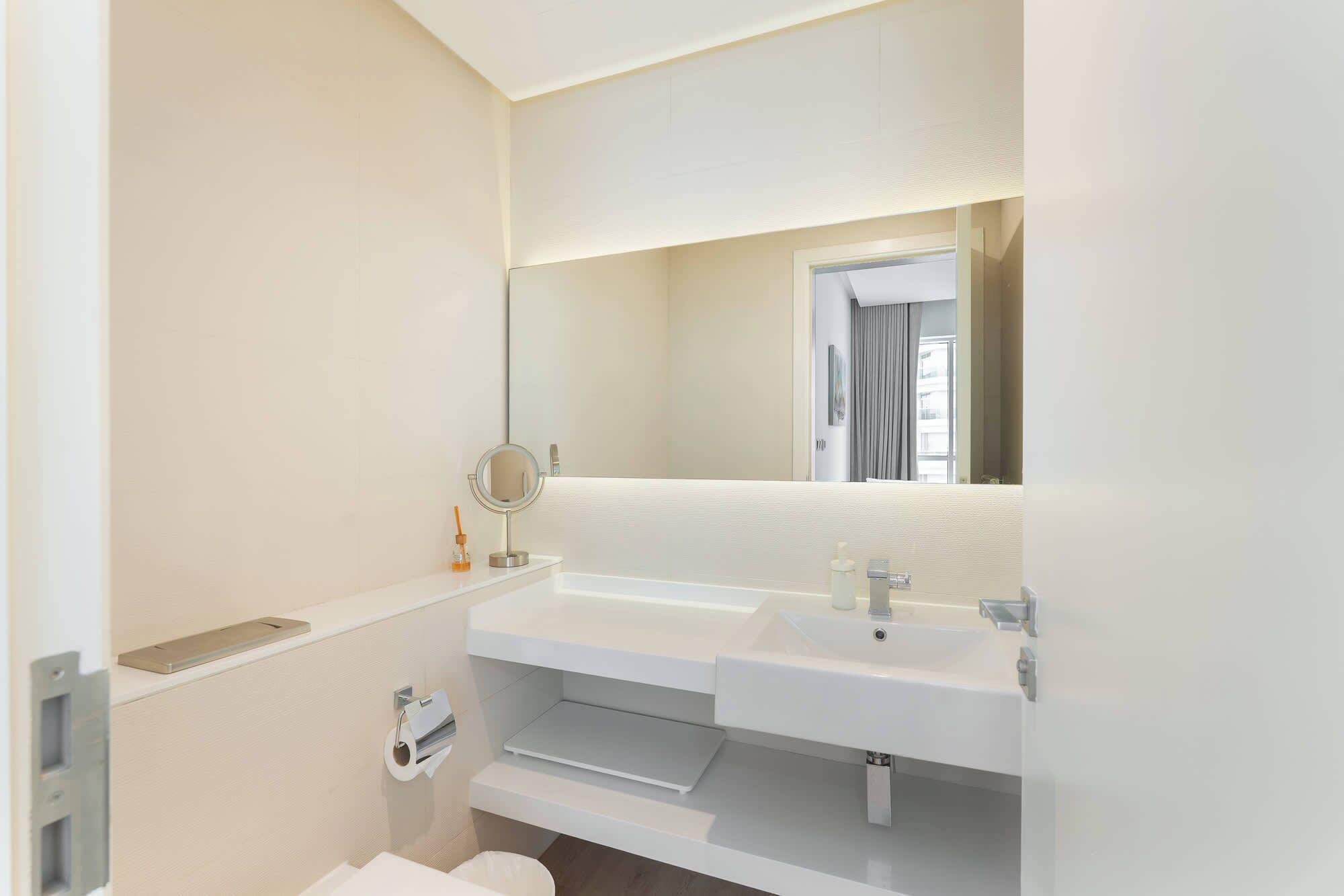 A modern bathroom with two sinks, a mirror, and a toilet.