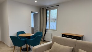 Un saló modern amb un sofà beix, dues cadires blaves, una taula de centre de fusta i un armari negre.