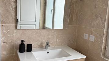 A bathroom with a white sink, a mirror above it, and beige tiled walls.