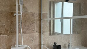 Un bany modern amb plat de dutxa de vidre, un envàs de color blanc i un mirall sobre l'envàs.