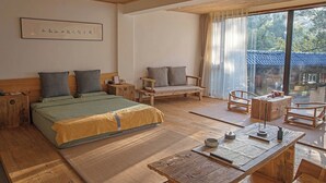 Una habitación con una cama, dos sillas, una mesa y un ventanal grande.