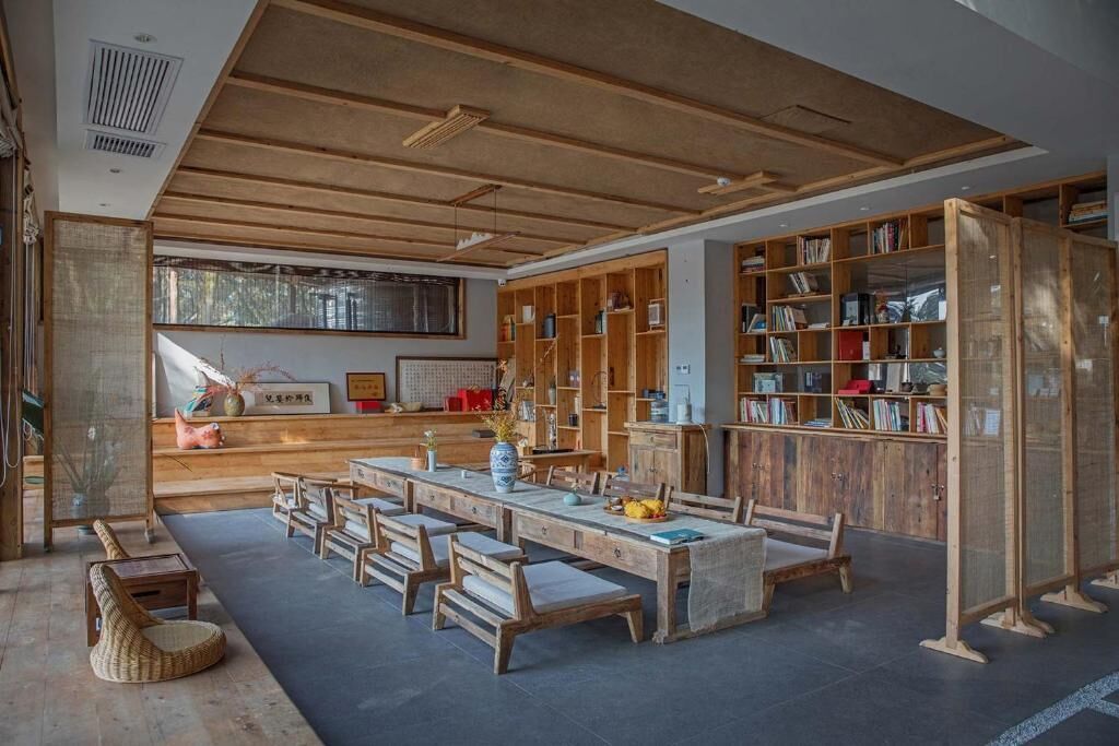 A spacious room with a long wooden table, several chairs, and a large bookshelf filled with books.