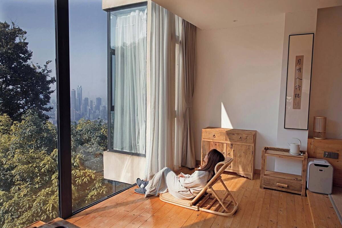 A modern room with a large window, a wooden floor, a wooden cabinet, and a small table with a teapot.