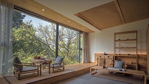 Una sala de estar moderna con ventanas amplias, muebles de madera y una estantería empotrada.