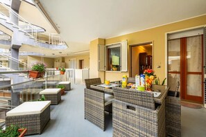 Ein geräumiger Balkon mit Korbmöbeln, Topfpflanzen und Blick ins Innere des Gebäudes.