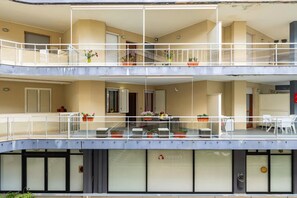 A multi-story building with balconies, potted plants, and a visible logo on the lower floor. - Spacious Apartment in Alghero (Alghero)