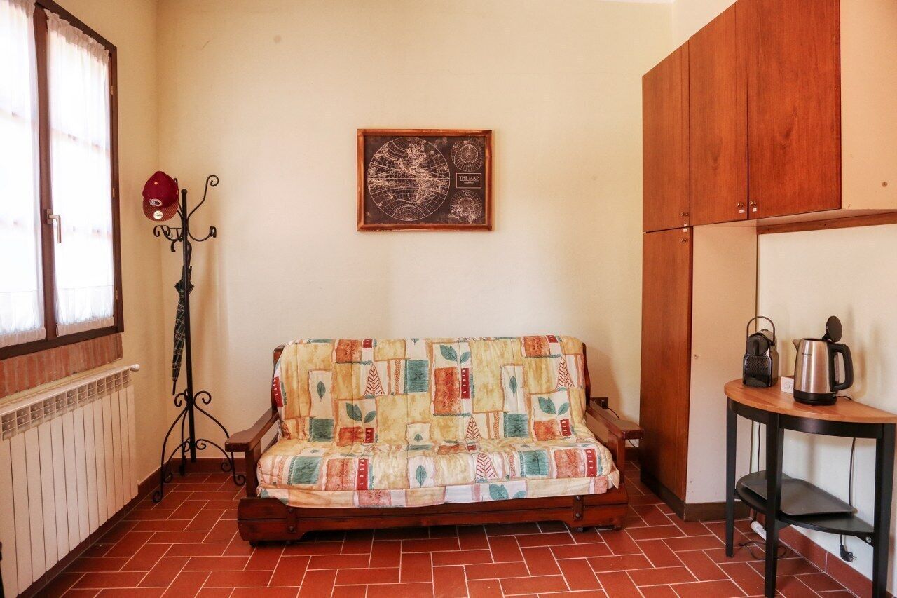 A cozy room with a wooden sofa, a radiator, a wall-mounted globe, and a small table with a kettle.