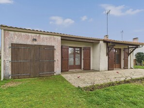 Ein zweistöckiges Haus mit Ziegeldach, einer Veranda und einer Garage mit Holztüren.