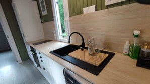 A modern kitchen with a black sink, wooden countertop, and a dishwasher.
