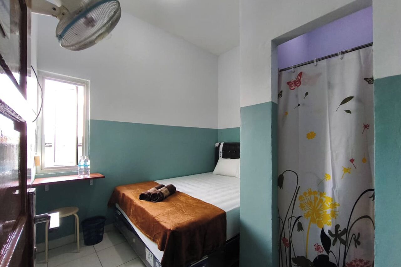A small, single-bed room with a window, a desk, and a chair.