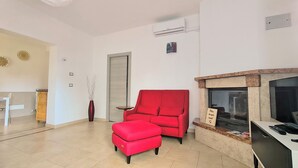 Ein Wohnzimmer mit rotem Sofa, Kamin und Fliesenboden.