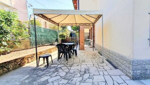 Ein überdachter Patio-Bereich mit Steinböden, einem Tisch und Stühlen.