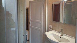 A bathroom with a white sink, a mirror, and a door leading to another room. - Bed in Siena (Siena)