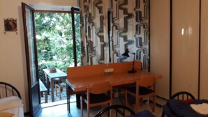 A room with a bed, a desk with a chair, a table with chairs, and a view of greenery outside. - Bed in Siena (Siena)