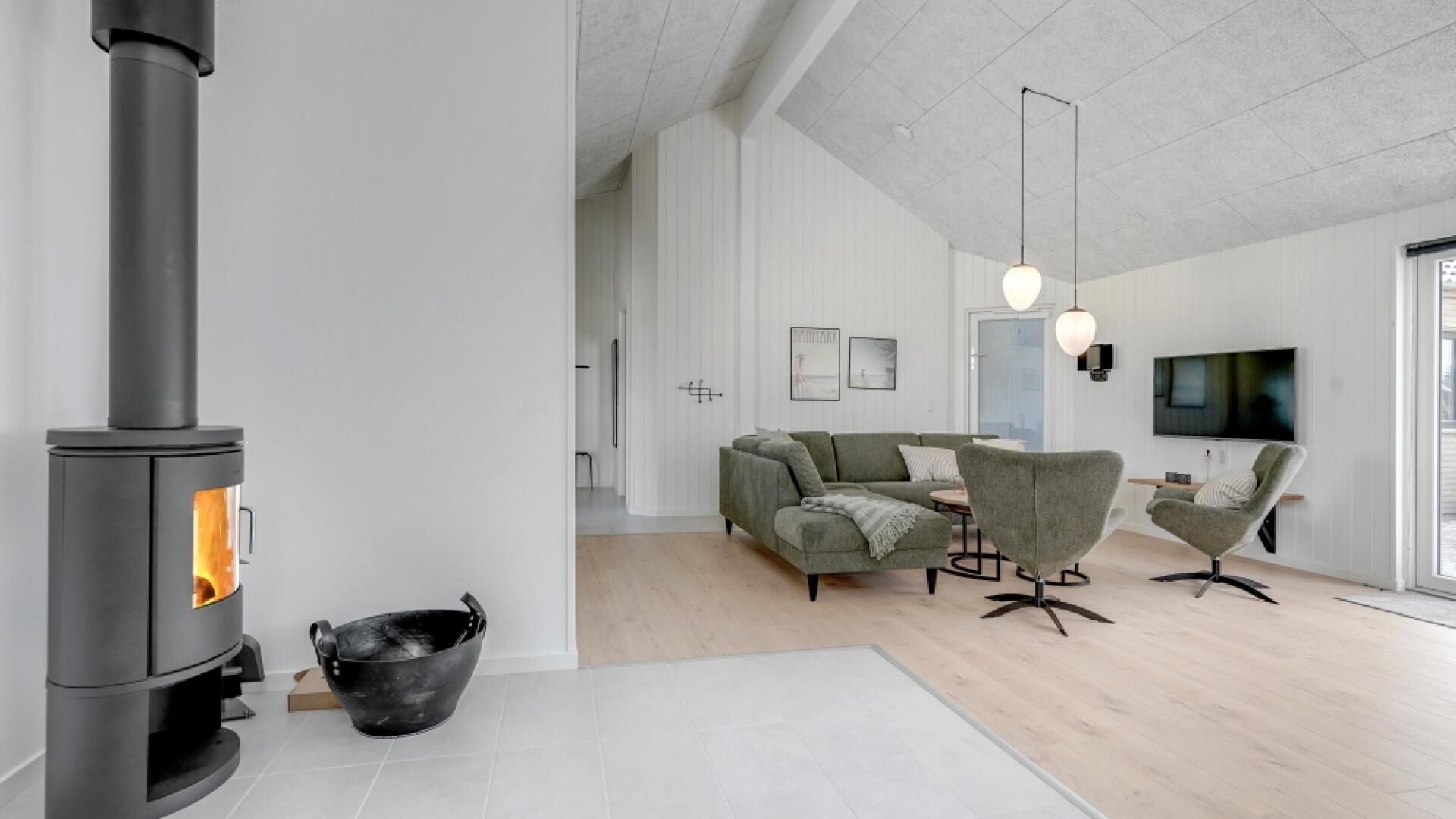 A modern living room with a wood-burning stove, a sofa set, and a dining table.