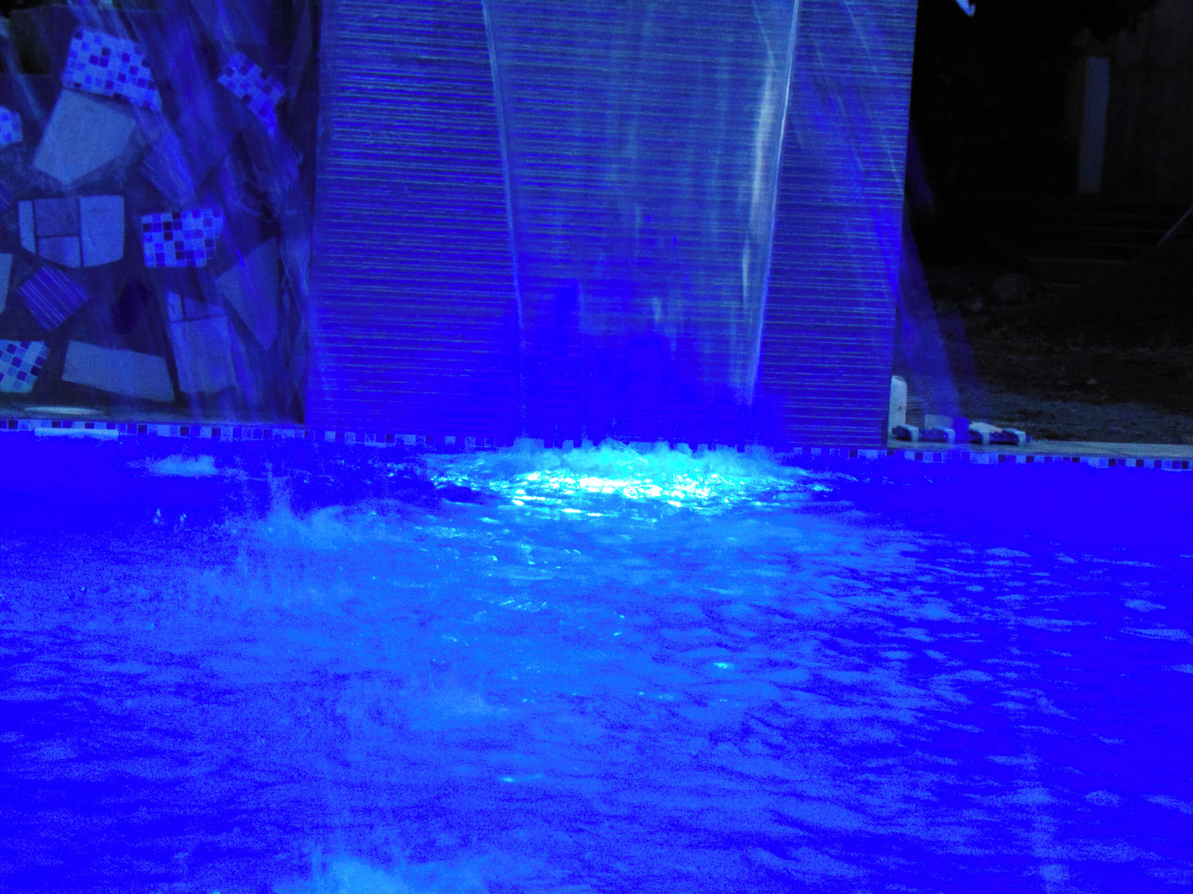 Une piscine agrémentée d’un élément décoratif aquatique illuminé de lumière bleue.
