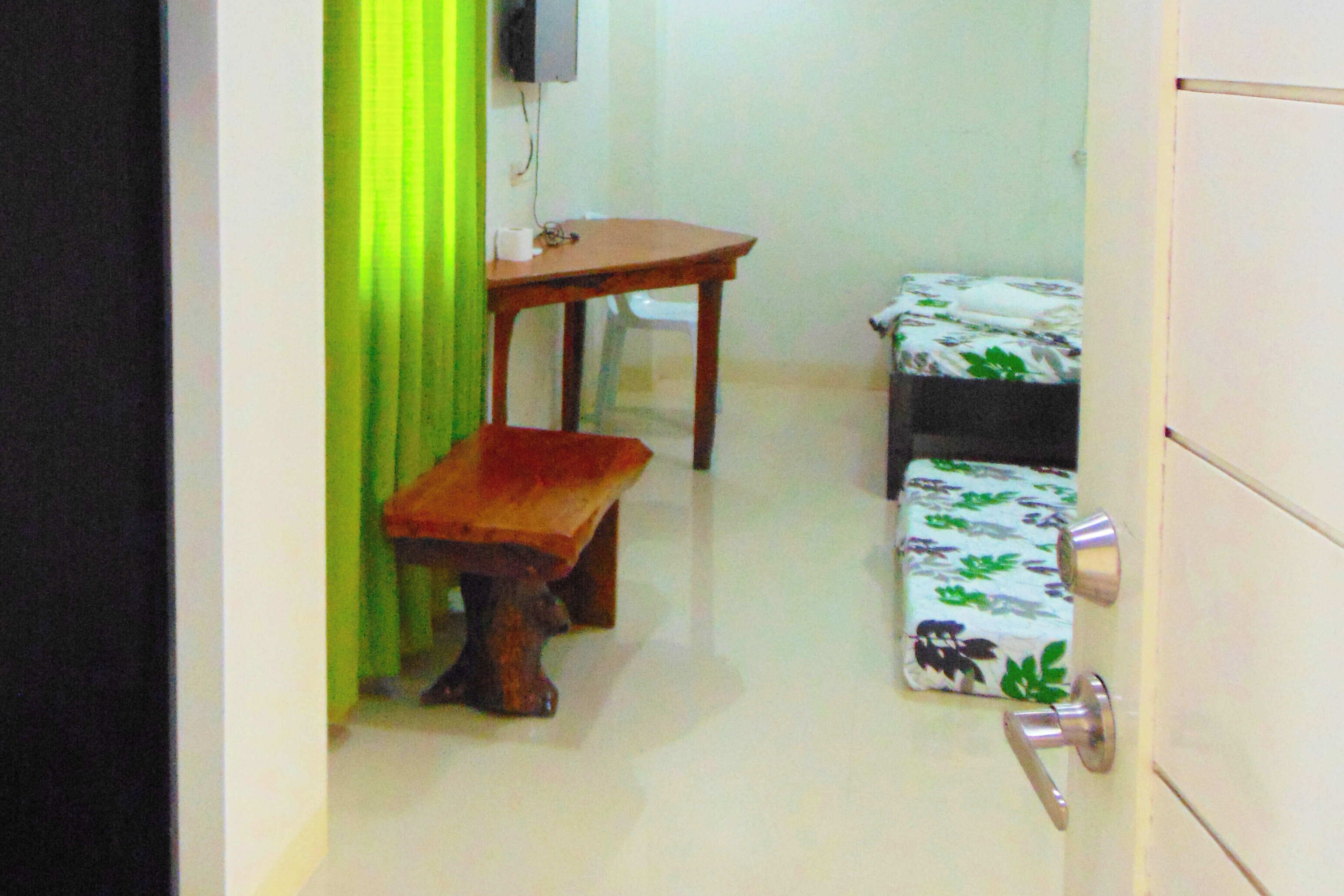 Un pasillo estrecho con un banco de madera, una mesita y una cama con ropa de cama floral.