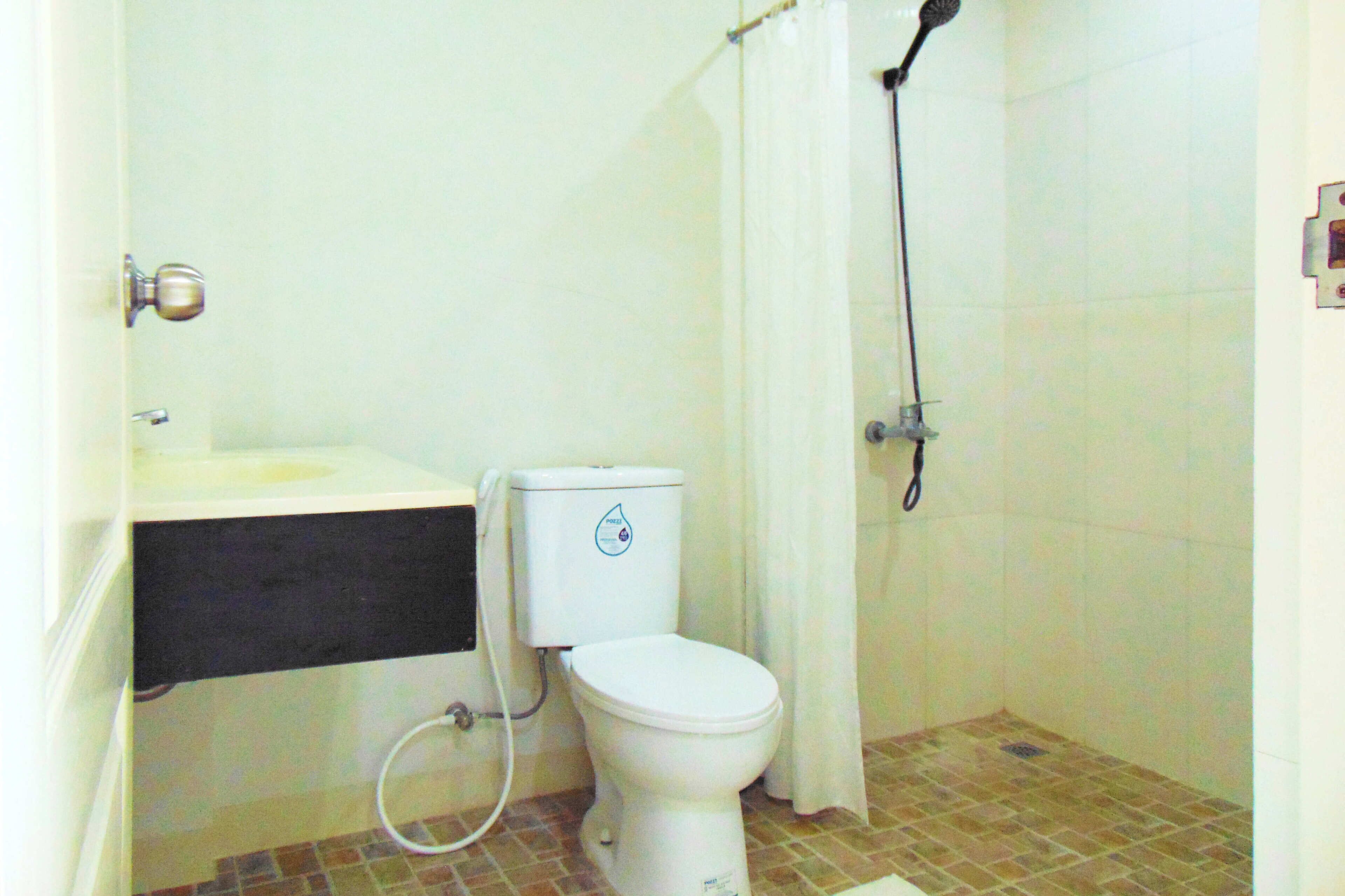 A small bathroom with a toilet, sink, and shower.