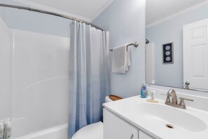 Un bagno con tenda da doccia, un water, un lavandino con rubinetto e uno specchio.