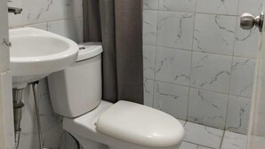 Un baño con inodoro, lavabo y zona de ducha.