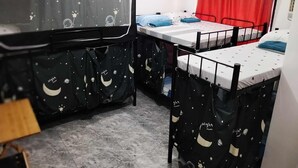 Un dormitorio con literas, un escritorio y una cortina roja.