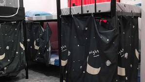 Un dormitorio con literas, una cortina roja y cortinas negras con motivos espaciales.