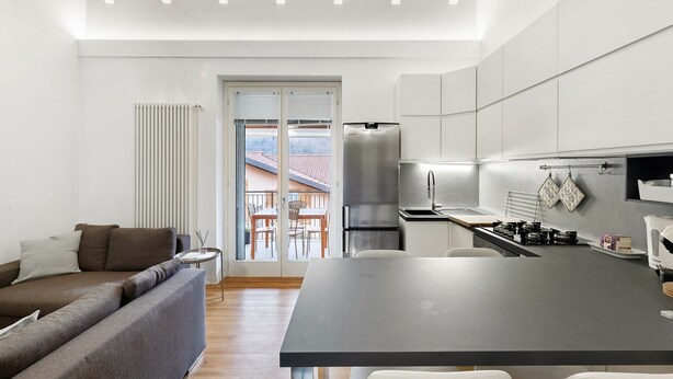 Une cuisine moderne avec un îlot central, un coin repas avec une table et des chaises, et un canapé dans l’espace salon.