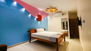 A bedroom with a bed, a wall-mounted air conditioner, a ceiling light fixture, and a door leading to another room.