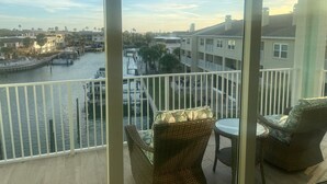 Un balcone con mobili in vimini, affacciato su una marina con barche ed edifici.