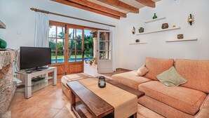 A living room with a TV, sofa, coffee table, and wooden beams on the ceiling.