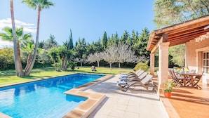 A swimming pool with lounge chairs and a patio area with a table and chairs.