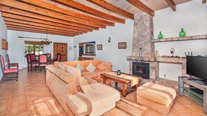 A spacious living room with a wooden ceiling, a fireplace, and a television.