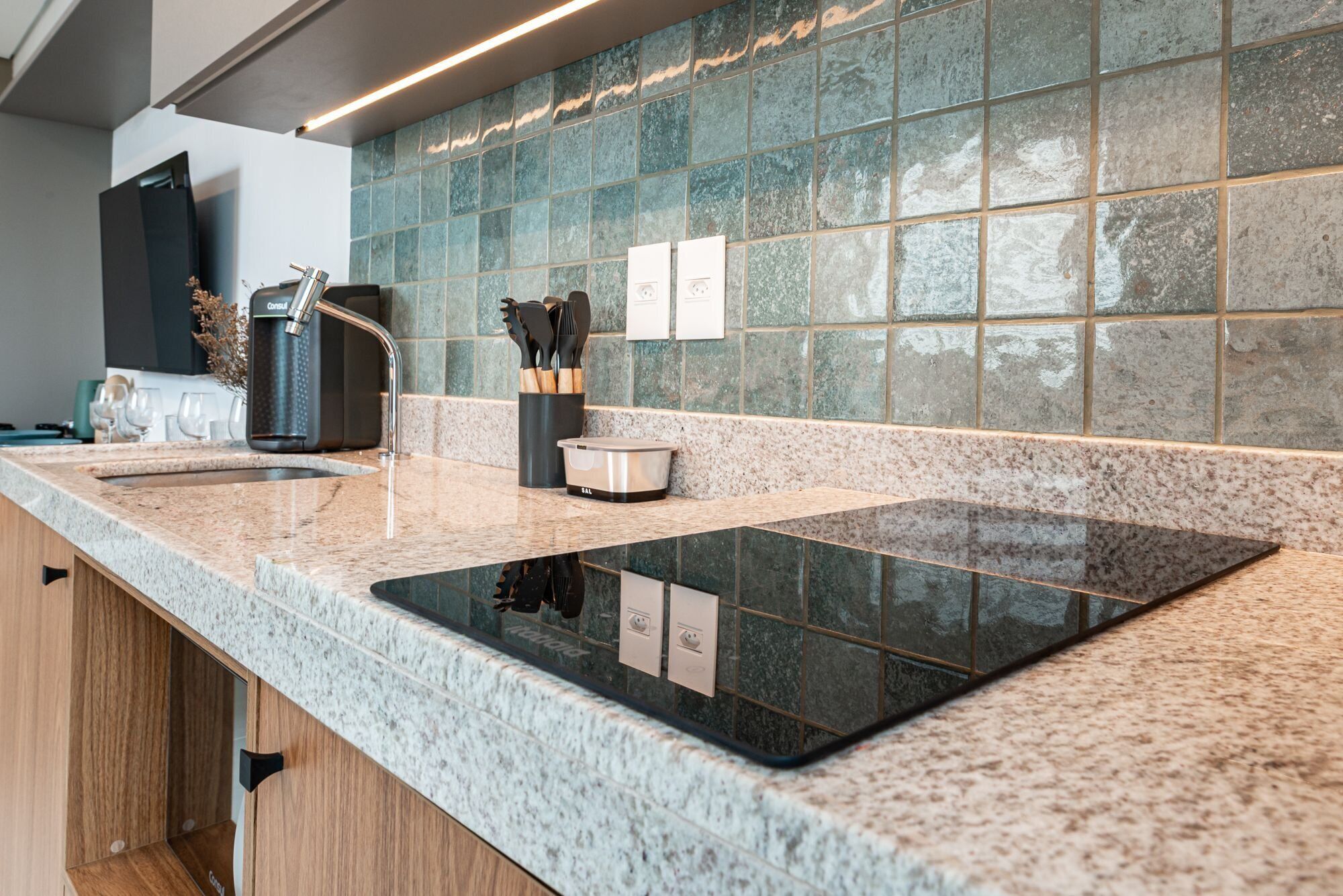 A kitchen with a granite countertop, a built-in stove, and a backsplash of square tiles.